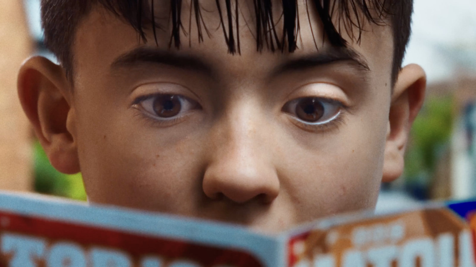 Boy in a red sweater reading a book
